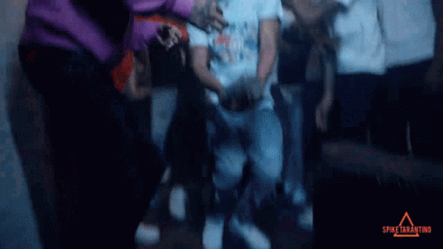 A Group Of People Are Gathered In A Dark Room With Spike Tarantino Written On The Bottom Right GIF