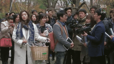 A Group Of People Are Gathered In Front Of A Sbs Sign GIF