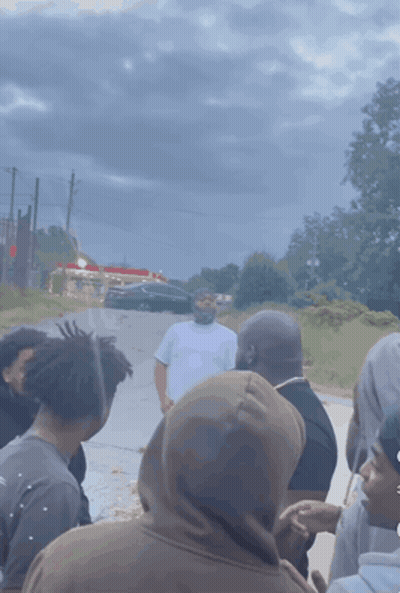 A Group Of People Are Gathered On The Side Of A Road GIF