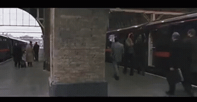 A Group Of People Are Getting On A Train At A Train Station GIF