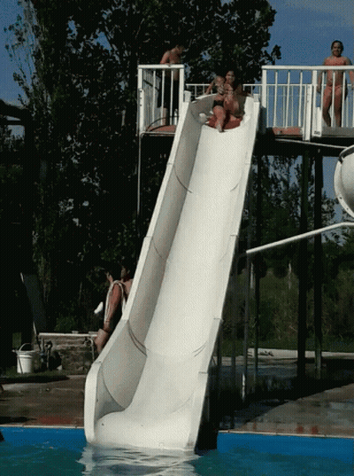 A Group Of People Are Going Down A Slide In A Pool GIF