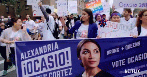 A Group Of People Are Holding A Banner That Says Alexandria Ocasio GIF