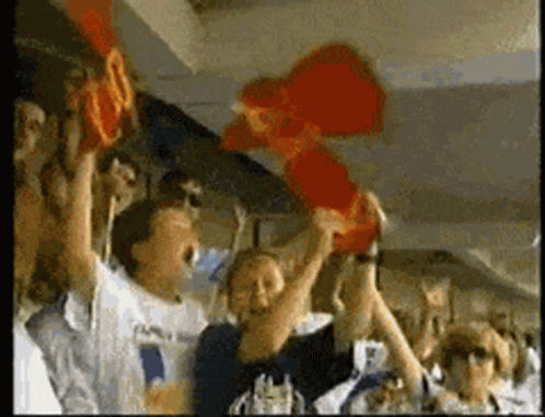 A Group Of People Are Holding Up A Red Object That Looks Like A Mcdonald 'S Logo GIF