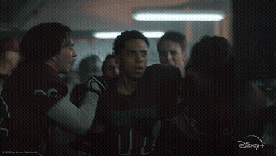 A Group Of People Are Huddled Together In A Dark Room With A Disney+ Logo In The Corner GIF