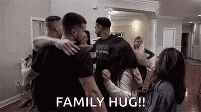 A Group Of People Are Hugging In A Living Room . GIF