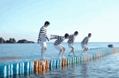 A Group Of People Are Jumping Over A Fence Into The Water . GIF