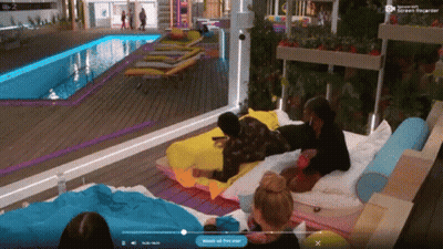 A Group Of People Are Laying On A Bed In Front Of A Pool And A Screen That Says " Watch Out For Now " GIF