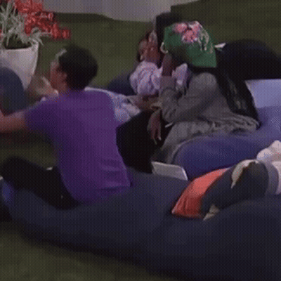A Group Of People Are Laying On A Couch With One Wearing A Hat That Says ' A ' On It GIF