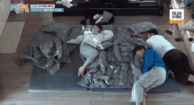 A Group Of People Are Laying On Top Of Each Other On A Mattress . GIF