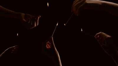 A Group Of People Are Lighting Matches In The Dark GIF