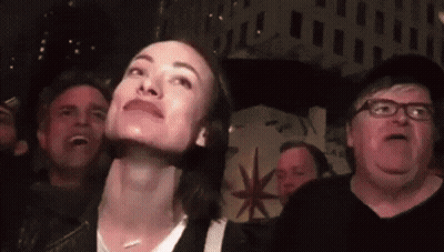 A Group Of People Are Looking Up At Something In A Dark Room GIF