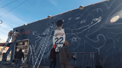 A Group Of People Are Painting A Mural Of A Man With The Number 22 On His Shirt GIF