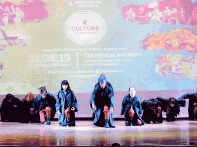 A Group Of People Are Performing On A Stage In Front Of A Large Screen That Says K Culture GIF