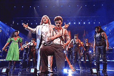 A Group Of People Are Performing On A Stage Including A Man Holding A Guitar . GIF