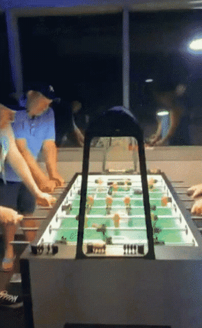 A Group Of People Are Playing A Game Of Foosball In A Room GIF