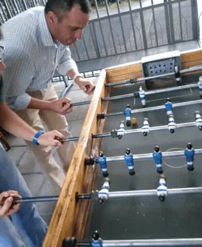 A Group Of People Are Playing A Game Of Foosball Outside GIF