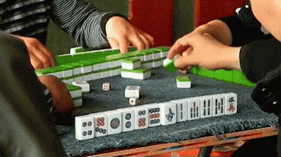 A Group Of People Are Playing A Game Of Mahjong With Dice . GIF