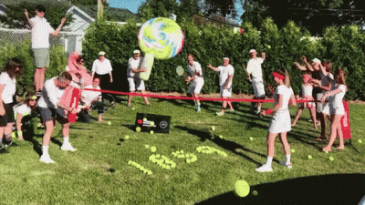 A Group Of People Are Playing A Game Of Tennis In A Grassy Area GIF