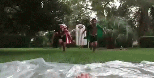A Group Of People Are Playing In A Water Slide In A Park . GIF