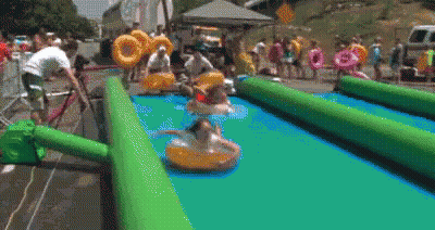 A Group Of People Are Playing On A Water Slide With Tubes . GIF