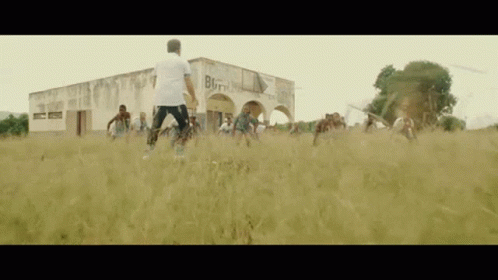 A Group Of People Are Playing Soccer In A Field In Front Of A Building That Has The Word Born On It GIF
