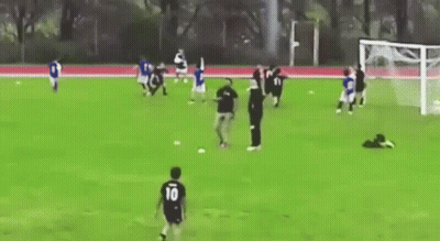A Group Of People Are Playing Soccer On A Field With A Goal . GIF