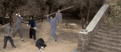 A Group Of People Are Playing With Sticks In A Field GIF