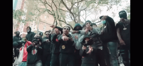 A Group Of People Are Posing For A Picture With One Wearing A Hoodie With A Smiley Face On It . GIF