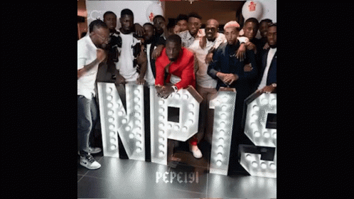 A Group Of People Are Posing In Front Of A Sign That Says Nipt9 GIF