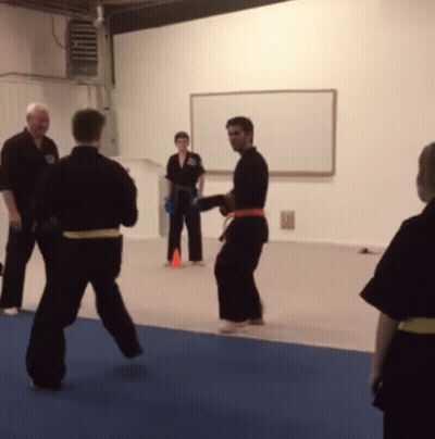 A Group Of People Are Practicing Martial Arts In Front Of A Whiteboard GIF