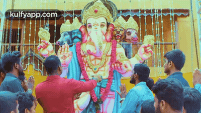 A Group Of People Are Praying In Front Of A Statue Of Ganesha . GIF
