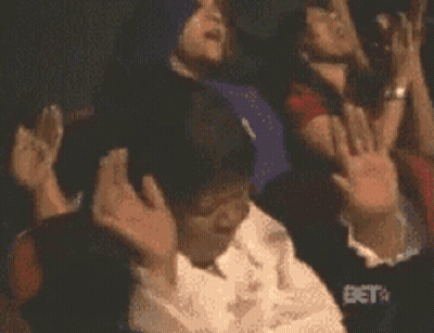 A Group Of People Are Raising Their Hands In The Air With Bet In The Background GIF