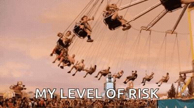 A Group Of People Are Riding A Merry Go Round At An Amusement Park With The Words " My Level Of Risk " Above Them GIF