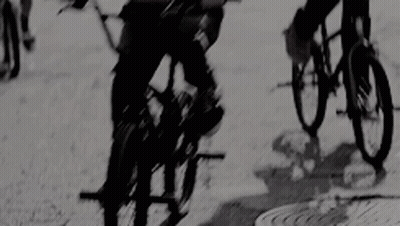 A Group Of People Are Riding Bikes Down A Street . GIF