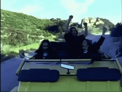 A Group Of People Are Riding In A Convertible Car On A Road . GIF