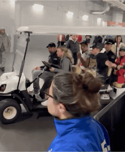 A Group Of People Are Riding In A Golf Cart And One Of Them Is Wearing A Blue Jacket With The Number 4 On It GIF
