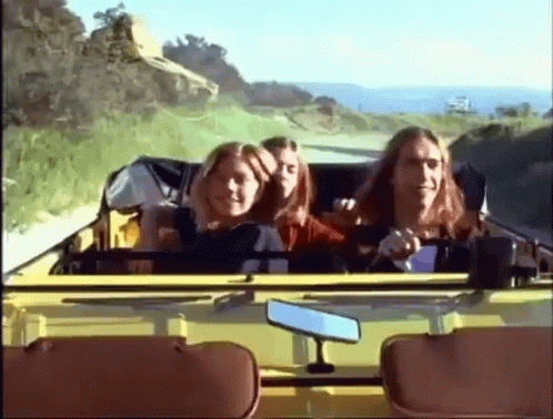 A Group Of People Are Riding In A Yellow Car On A Country Road GIF
