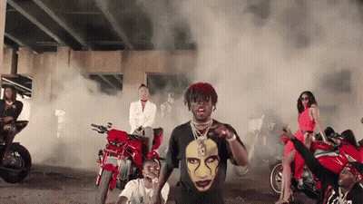 A Group Of People Are Riding Motorcycles Under A Bridge And Smoke Is Coming Out Of The Motorcycles . GIF
