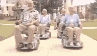 A Group Of People Are Riding Scooters Down A Sidewalk . GIF