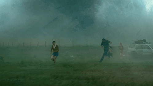 A Group Of People Are Running From A Tornado In A Field GIF