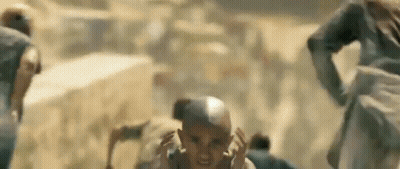 A Group Of People Are Running In The Desert And A Man Is Screaming . GIF