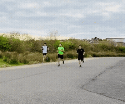 A Group Of People Are Running On A Road . GIF