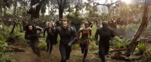 A Group Of People Are Running Through A Forest In A Movie . GIF