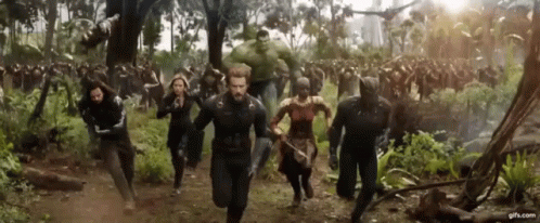 A Group Of People Are Running Through A Forest In A Movie Scene . GIF