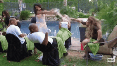 A Group Of People Are Sitting Around A Table And Chairs In Front Of A Pool . GIF