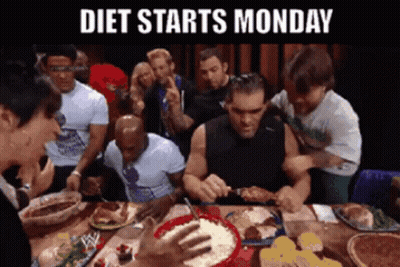 A Group Of People Are Sitting Around A Table Eating Food With The Words Diet Starts Monday Above Them GIF