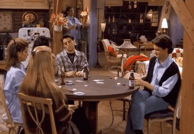 A Group Of People Are Sitting Around A Table Playing Cards With Bottles Of Beer . GIF