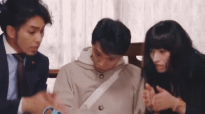 A Group Of People Are Sitting Around A Table Talking . GIF