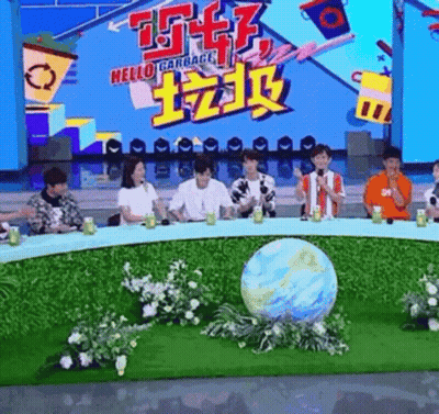 A Group Of People Are Sitting Around A Table With A Globe In The Middle Of The Table . GIF