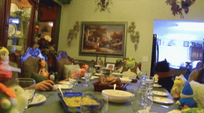 A Group Of People Are Sitting Around A Table With Plates And Glasses GIF